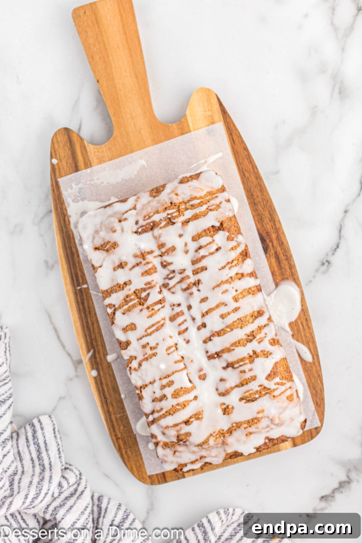 Bread on parchment paper with glaze drizzled on bread. 