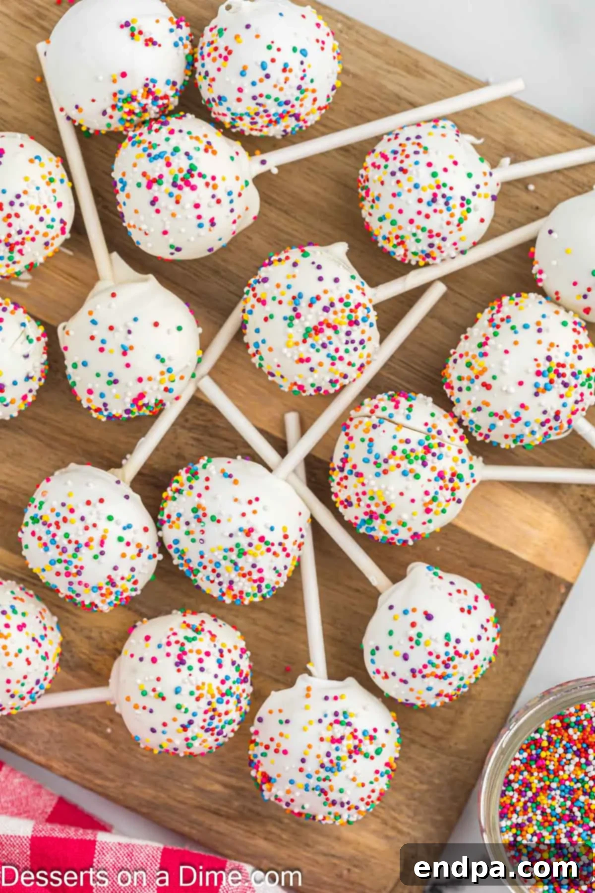 Whip Up Perfect Cake Pops 12 Beautifully decorated cake pops arranged on a rustic wooden board.