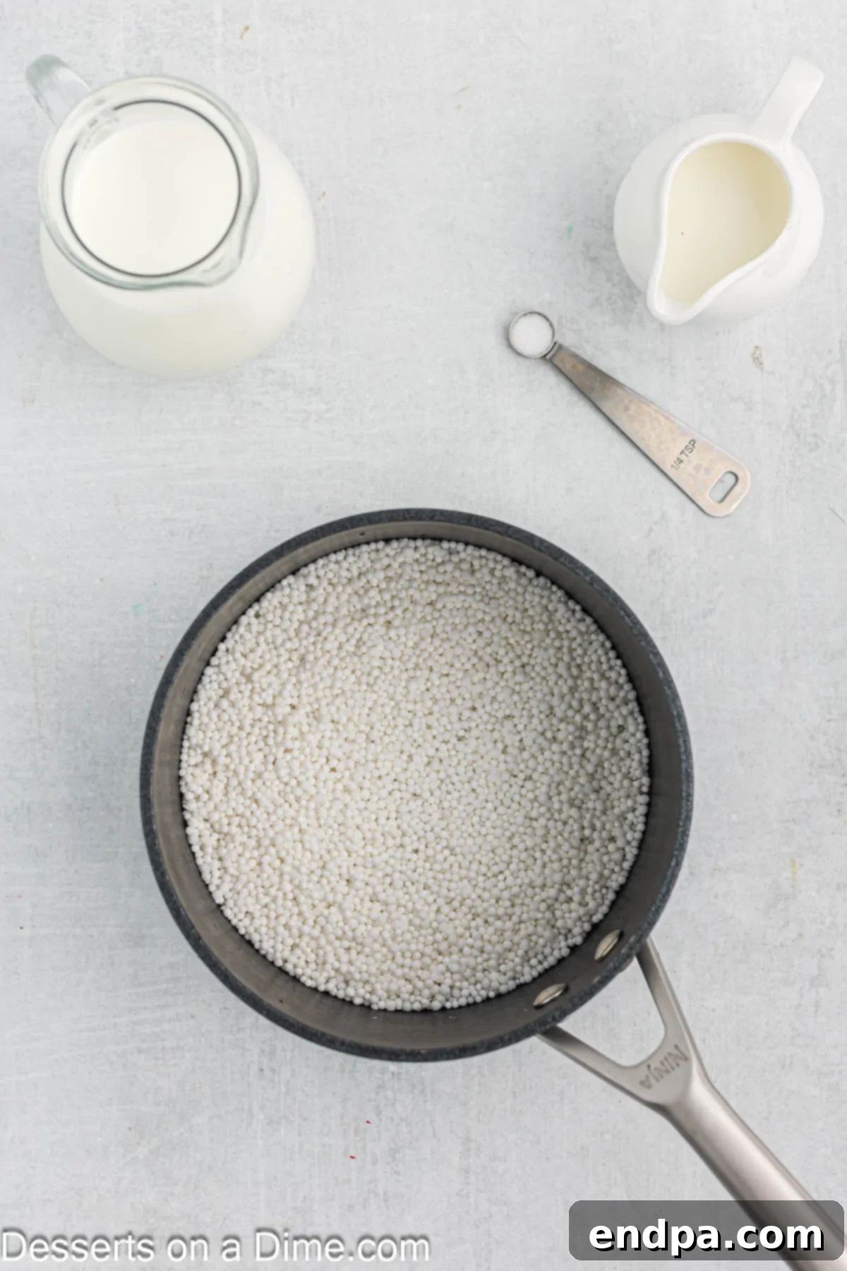 A saucepan showing small tapioca pearls soaking in water, beginning to plump up.