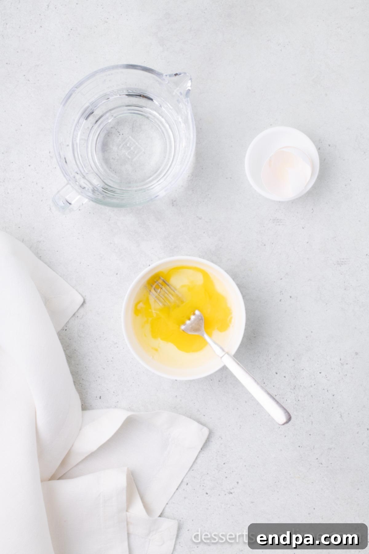 Small bowl containing a whisked egg and water mixture, ready for the egg wash.