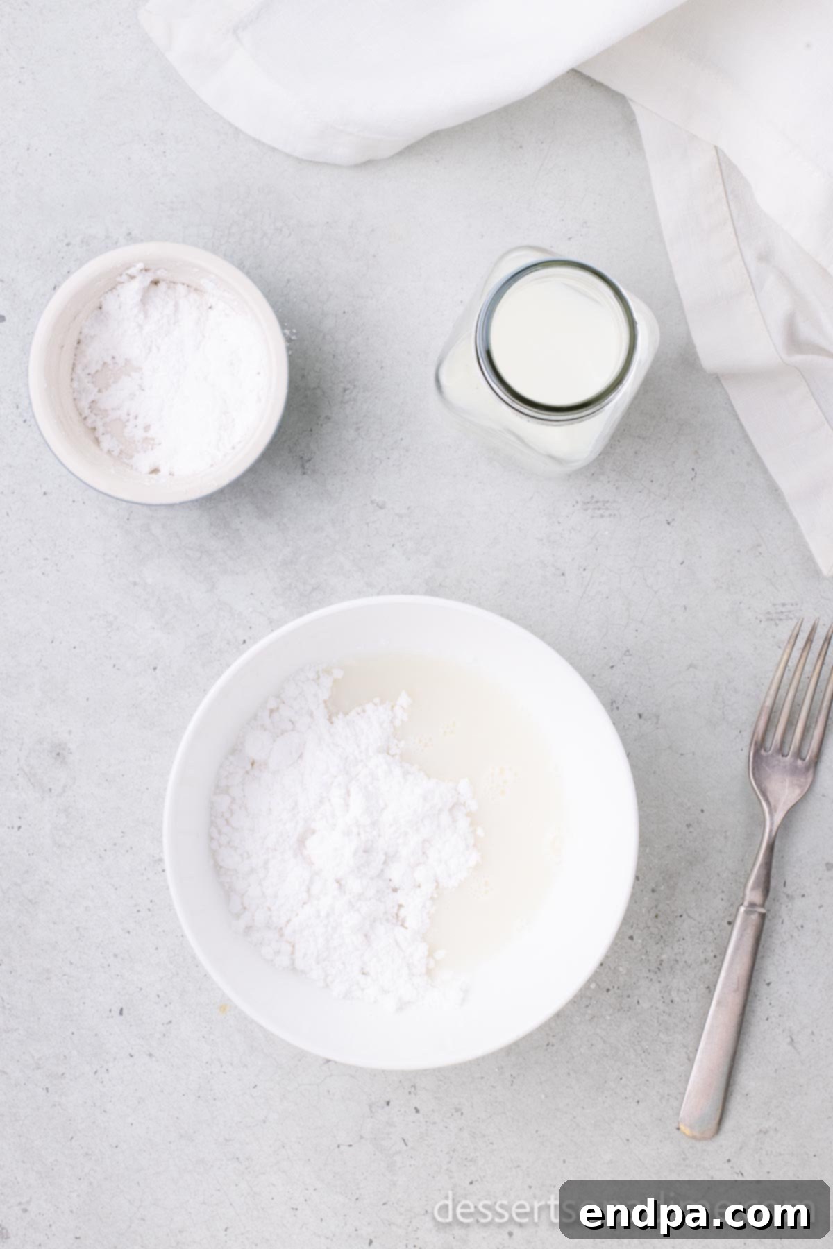 Small bowl containing powdered sugar and milk, whisked together to form a smooth glaze.
