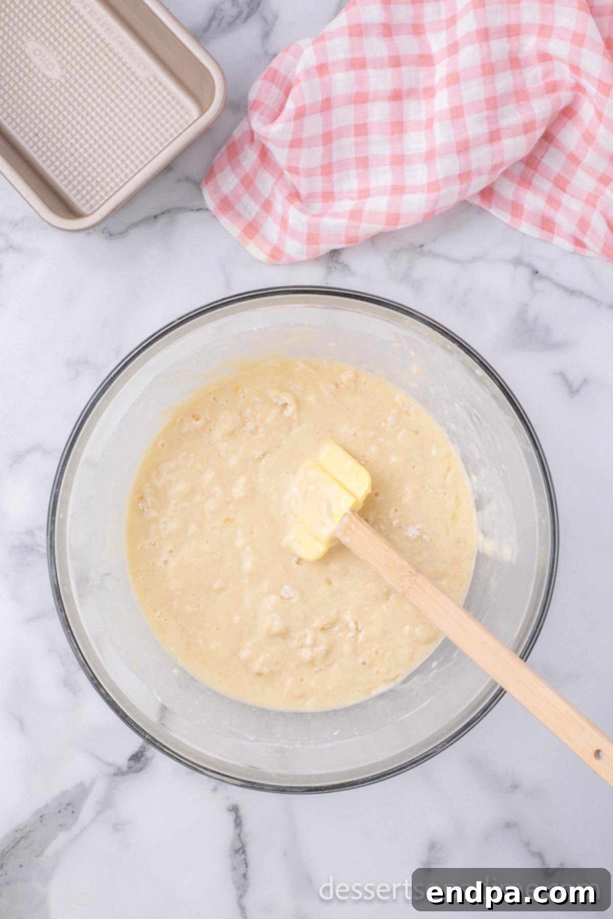 Large mixing bowl illustrating the dry and wet ingredients being gently combined with a wooden spoon, forming a thick, slightly lumpy batter.