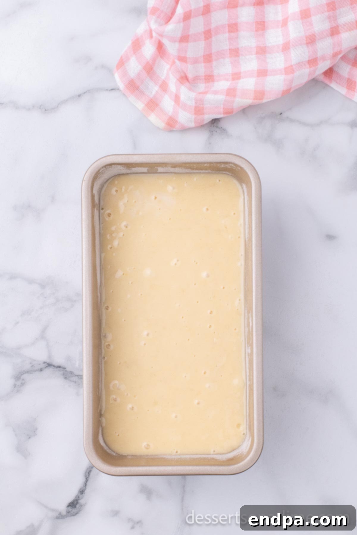The prepared loaf pan filled with the sweet bread batter, evenly spread and ready to be placed in the oven for baking.