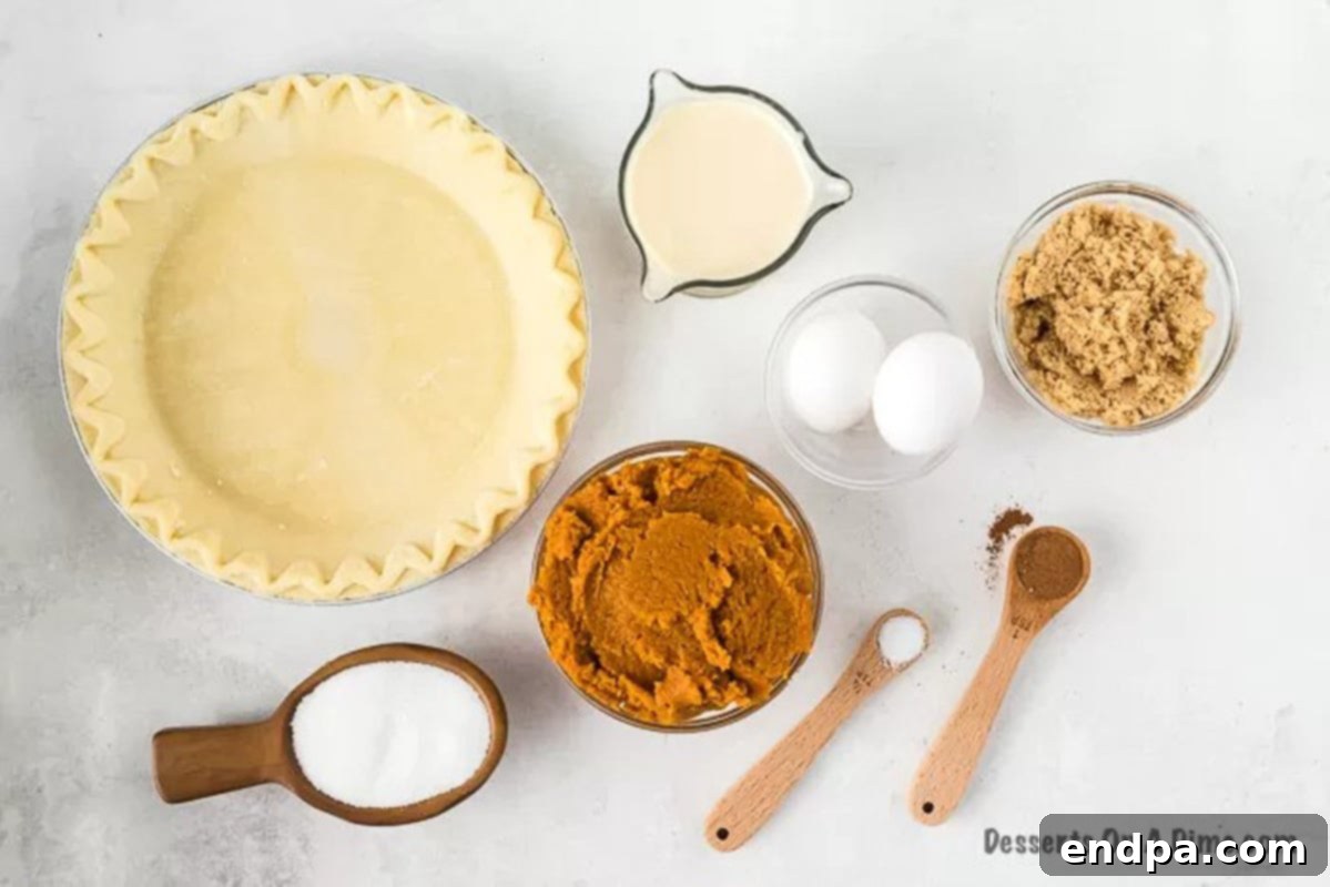 A flat lay image displaying all the essential ingredients for making an easy pumpkin pie, including an unbaked pie crust, brown sugar, white sugar, salt, pumpkin pie spice, eggs, pumpkin puree, and evaporated milk.