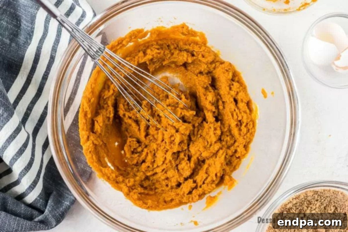 Beaten eggs are mixed into pumpkin puree in a large bowl, followed by the dry spice mixture, creating a thick, orange-colored filling base.