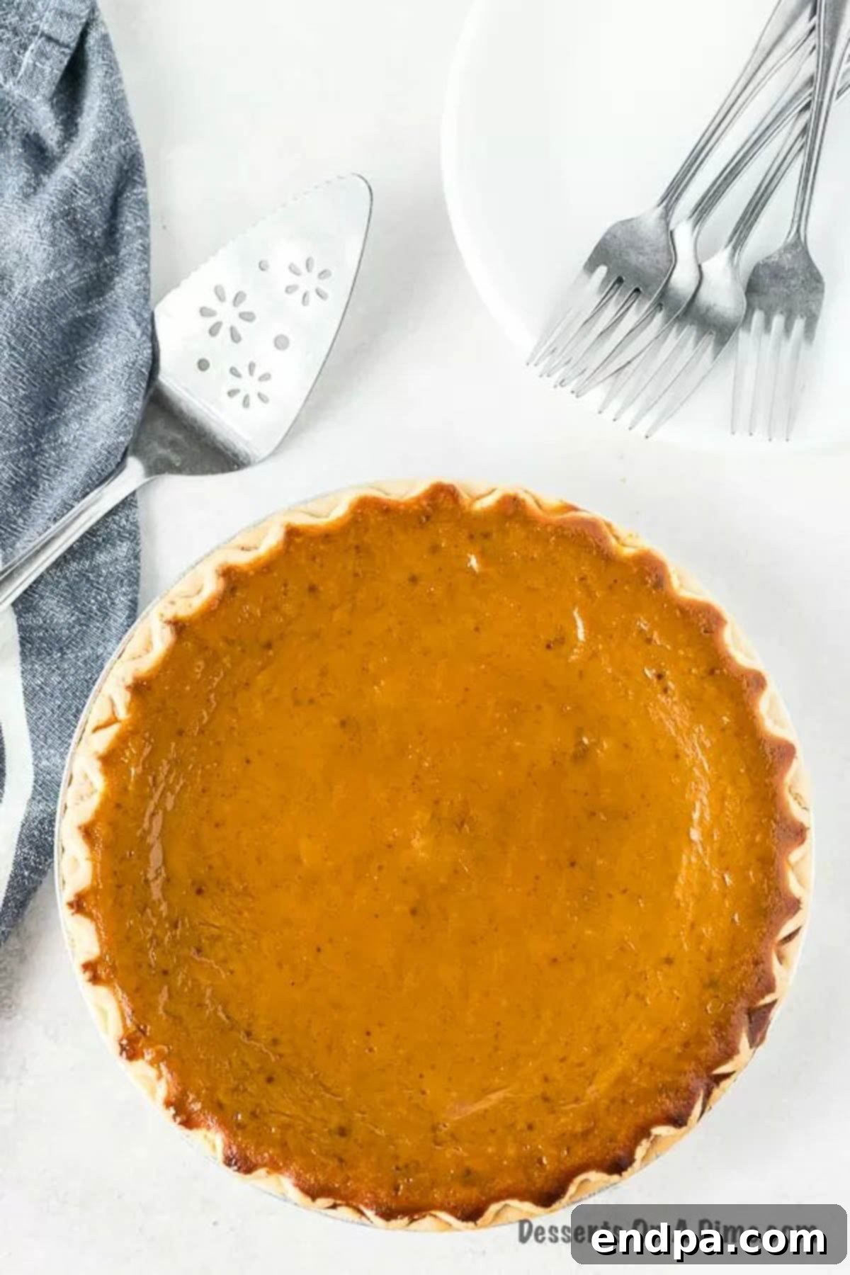A beautiful, whole homemade pumpkin pie, perfectly baked and golden brown, ready to be sliced and enjoyed.