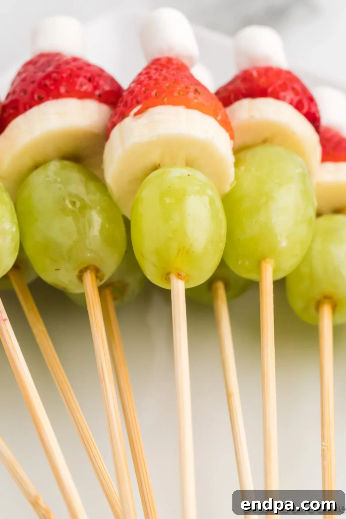 Grinch Fruit skewers neatly stacked together on a platter, highlighting their festive and appealing arrangement.