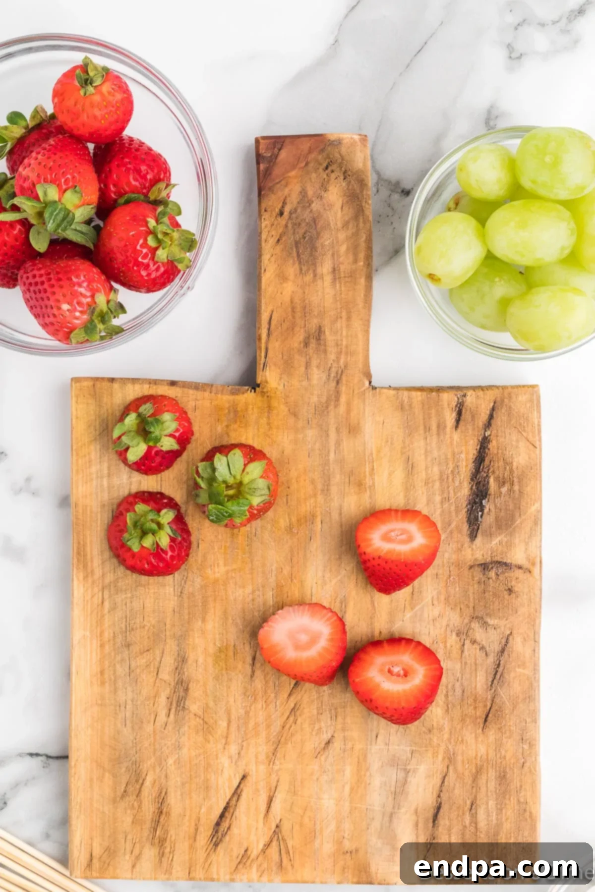 Fresh strawberries with their green tops neatly cut off, ready for assembly into Grinch kabobs.