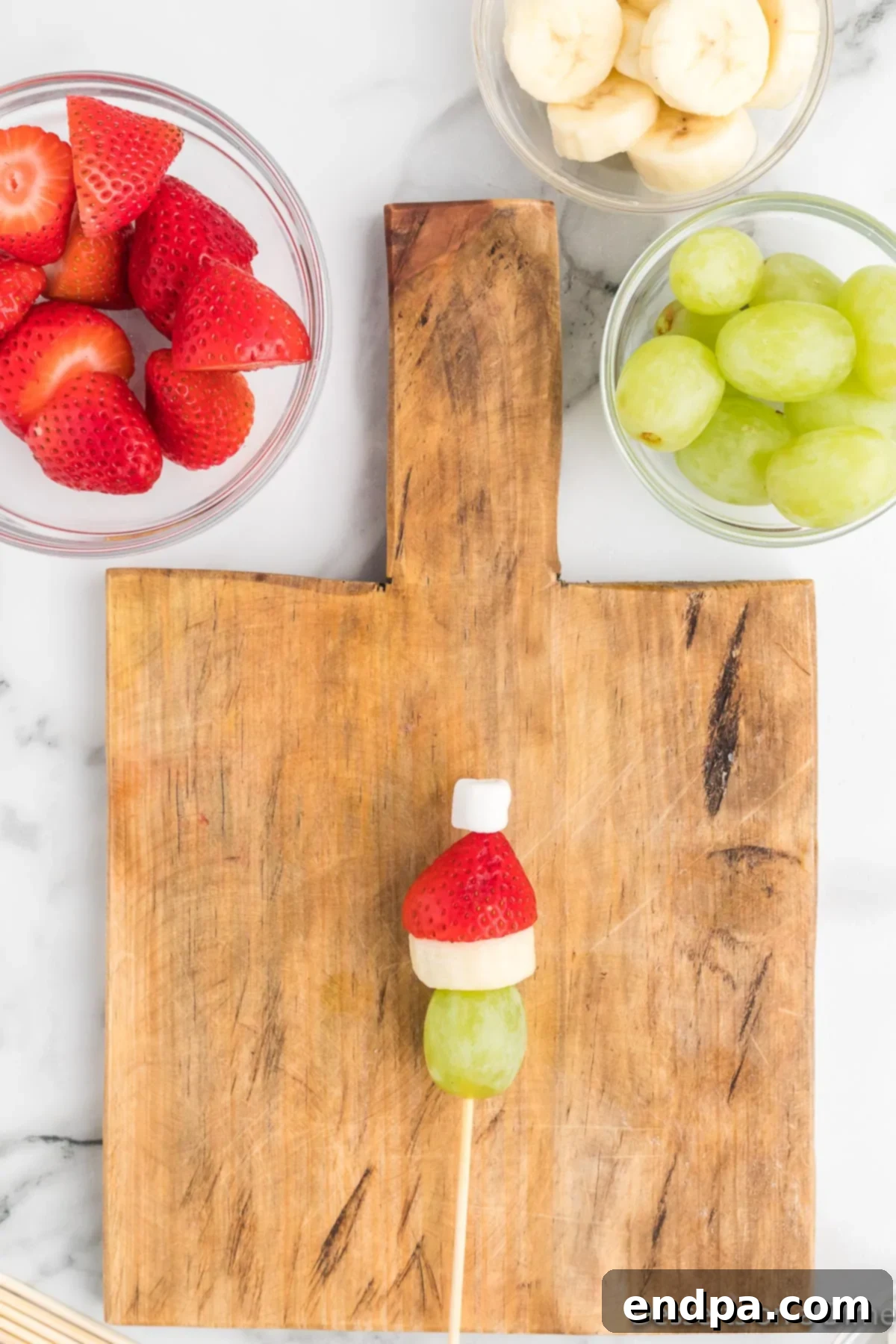 A mini marshmallow placed on the very top of the strawberry, serving as the pom-pom of the Grinch's Santa hat.
