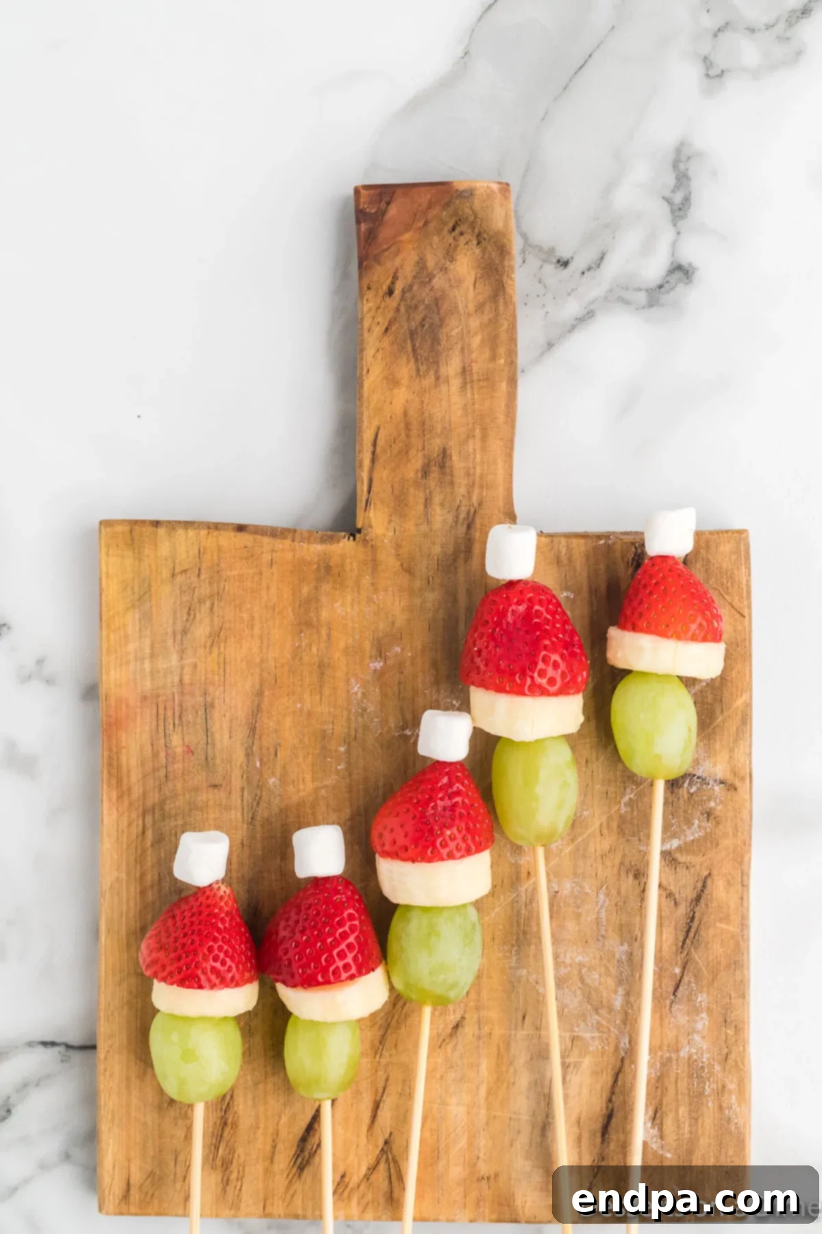 Multiple Grinch Fruit Skewers neatly arranged on a wooden board, showcasing the finished product before serving.