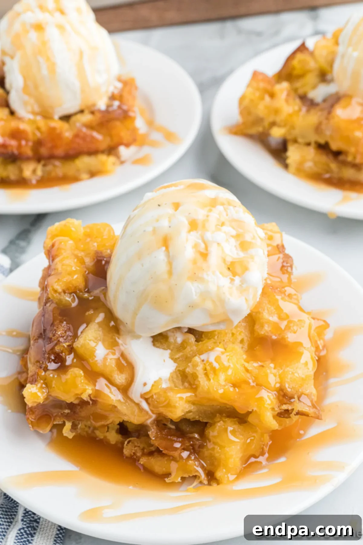 Tropical Pineapple Bread Pudding 2 Serving of bread pudding topped with ice cream and caramel.