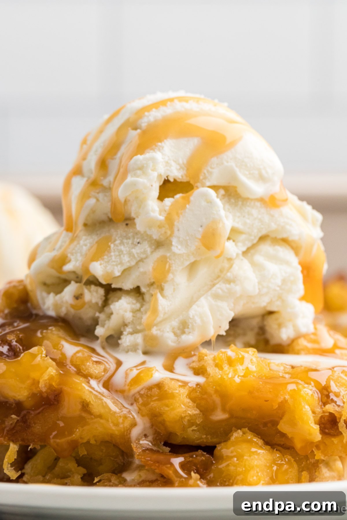 Tropical Pineapple Bread Pudding 9 Bread pudding in a bowl topped with ice cream and caramel sauce.