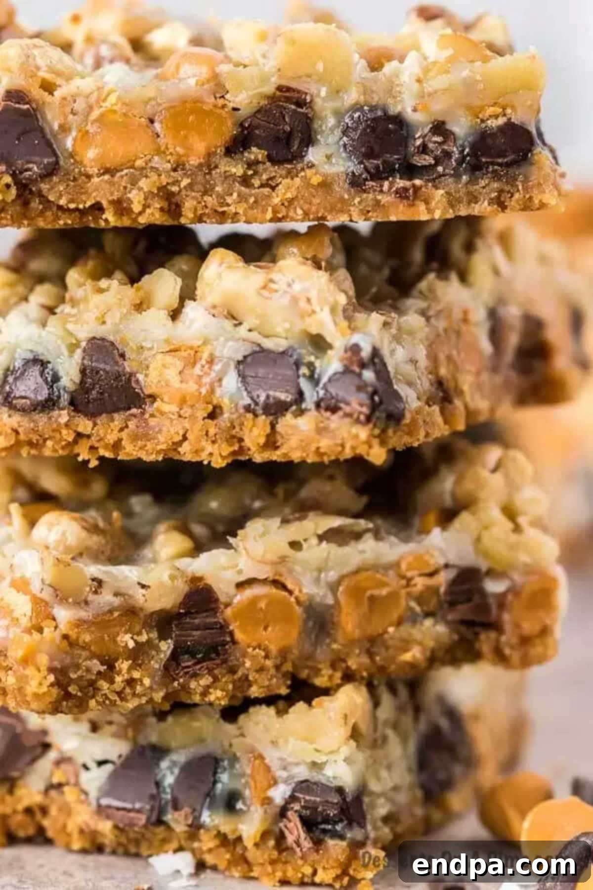 Enjoy decadent layers of chocolate chips, butterscotch, nuts and more in this Magic cookie bars recipe. Each bite is heavenly. Magic Cookie bar cookies are perfect for Christmas, 4th of July and more. Seven layer bars are easy and the best dessert with butterscotch. Everyone will love the 7 layer recipe. #dessertonadime #magiccookiebarsrecipe #eaglebrand #7layer Perfectly cut Magic Bars stacked, showcasing their distinct seven layers