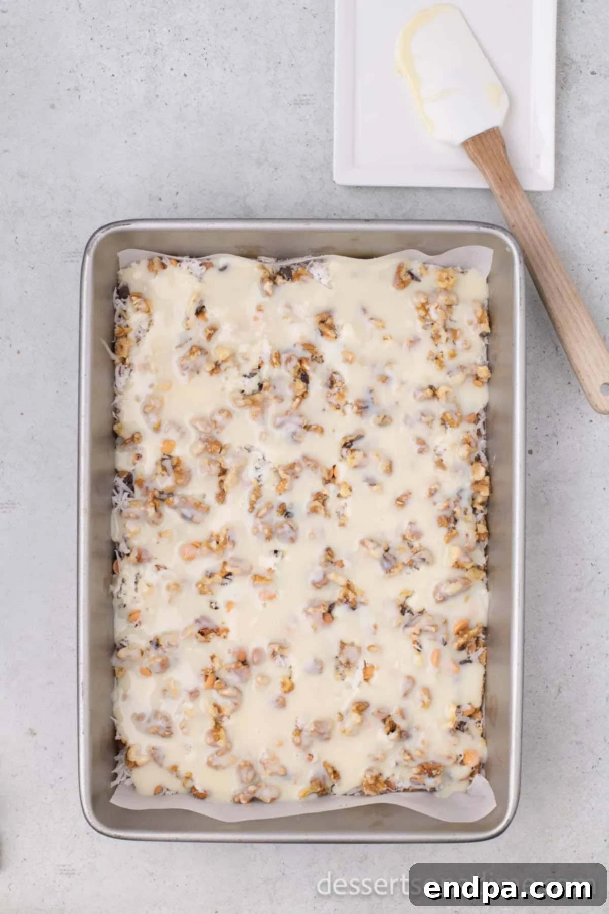 Irresistible Magic Cookie Bars Recipe 7 Sweetened condensed milk poured over the layered ingredients.