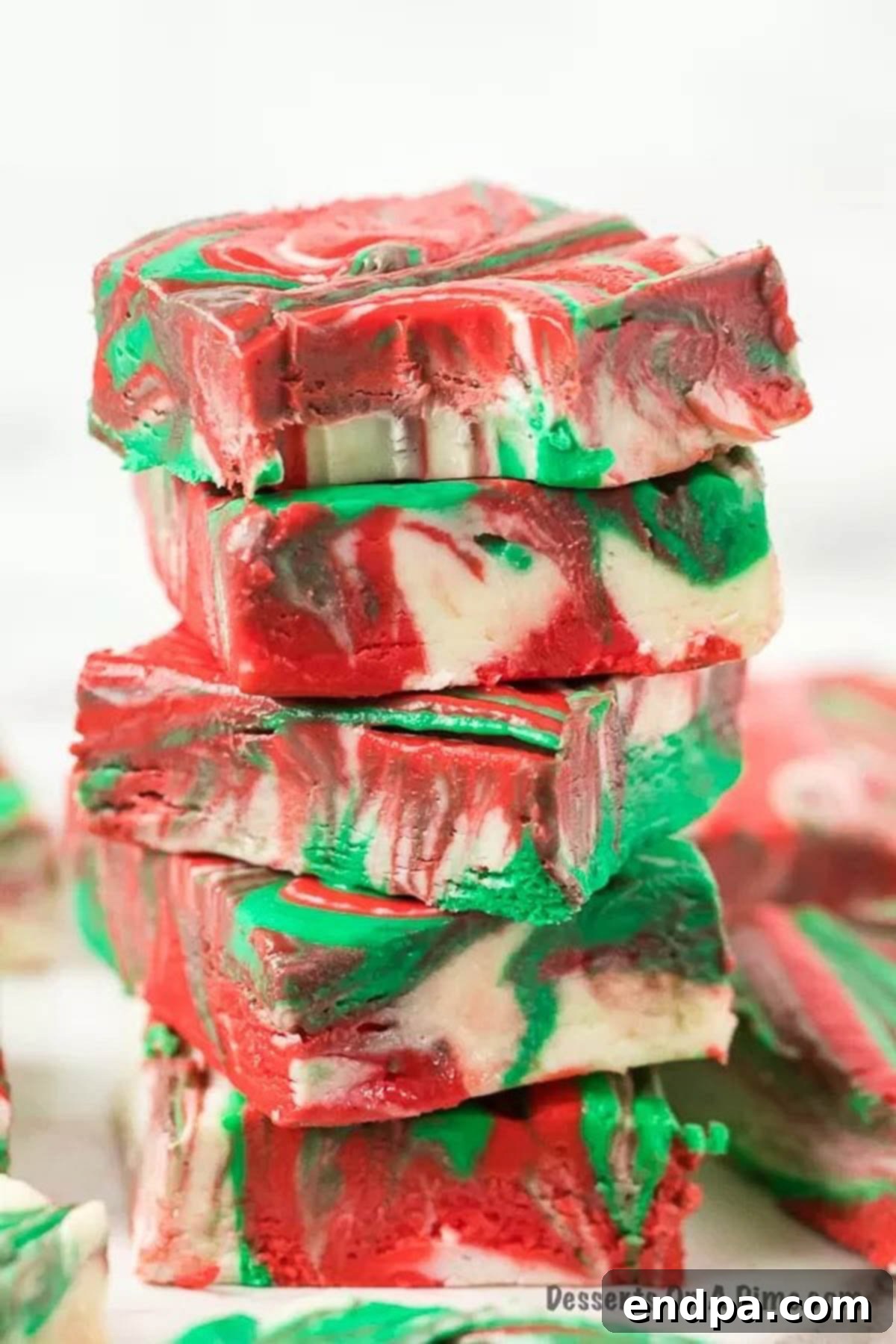 A stack of beautifully swirled Christmas fudge squares, showcasing their vibrant colors and creamy texture.