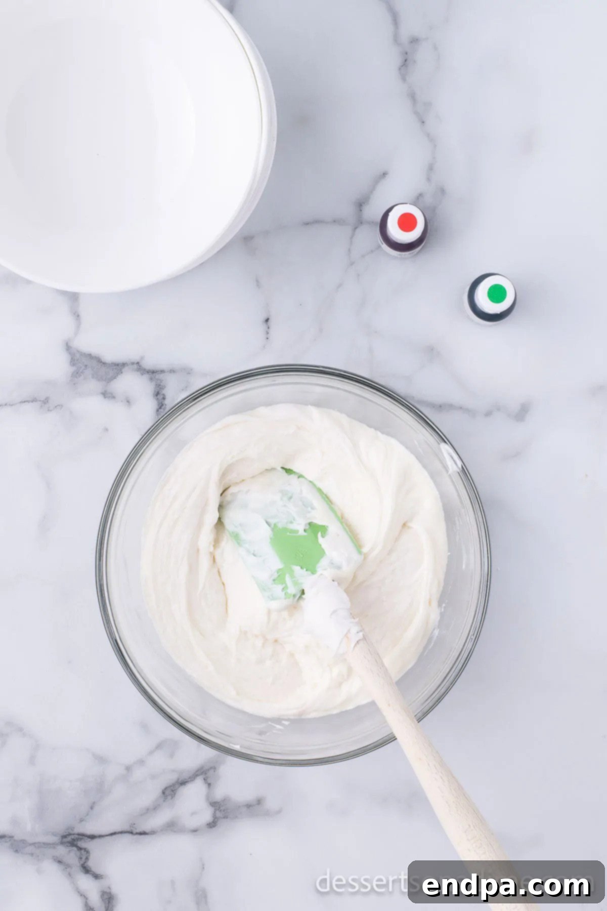 Vanilla frosting being stirred into the melted white chocolate.