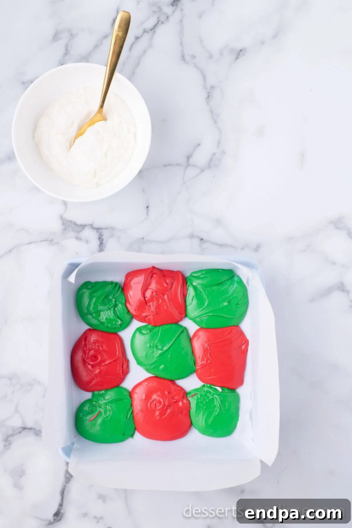 Spoonfuls of red, green, and white fudge mixture randomly dropped into the prepared pan.