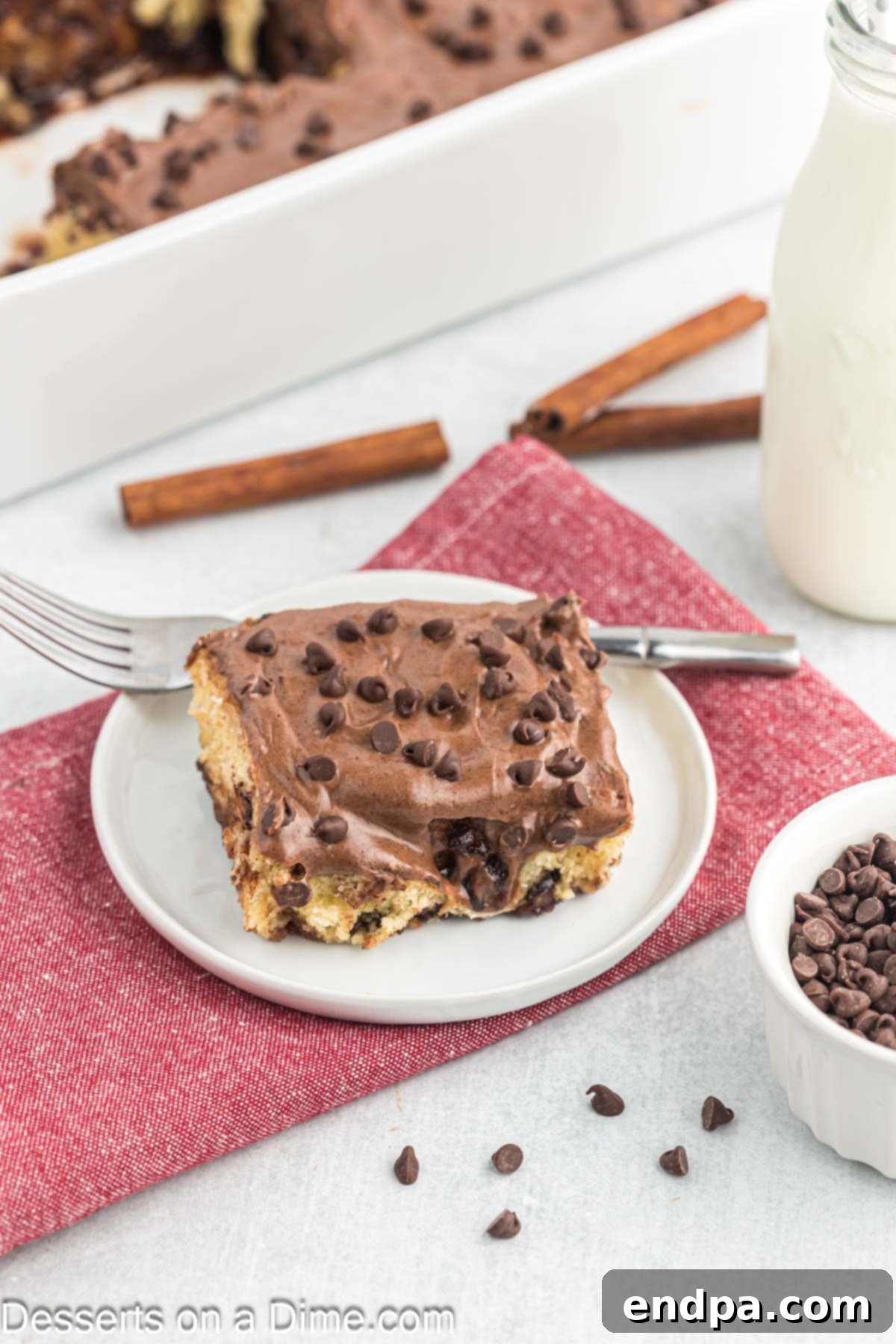 Freshly baked Chocolate Chip Cinnamon Rolls on a plate, generously drizzled with cream cheese icing.