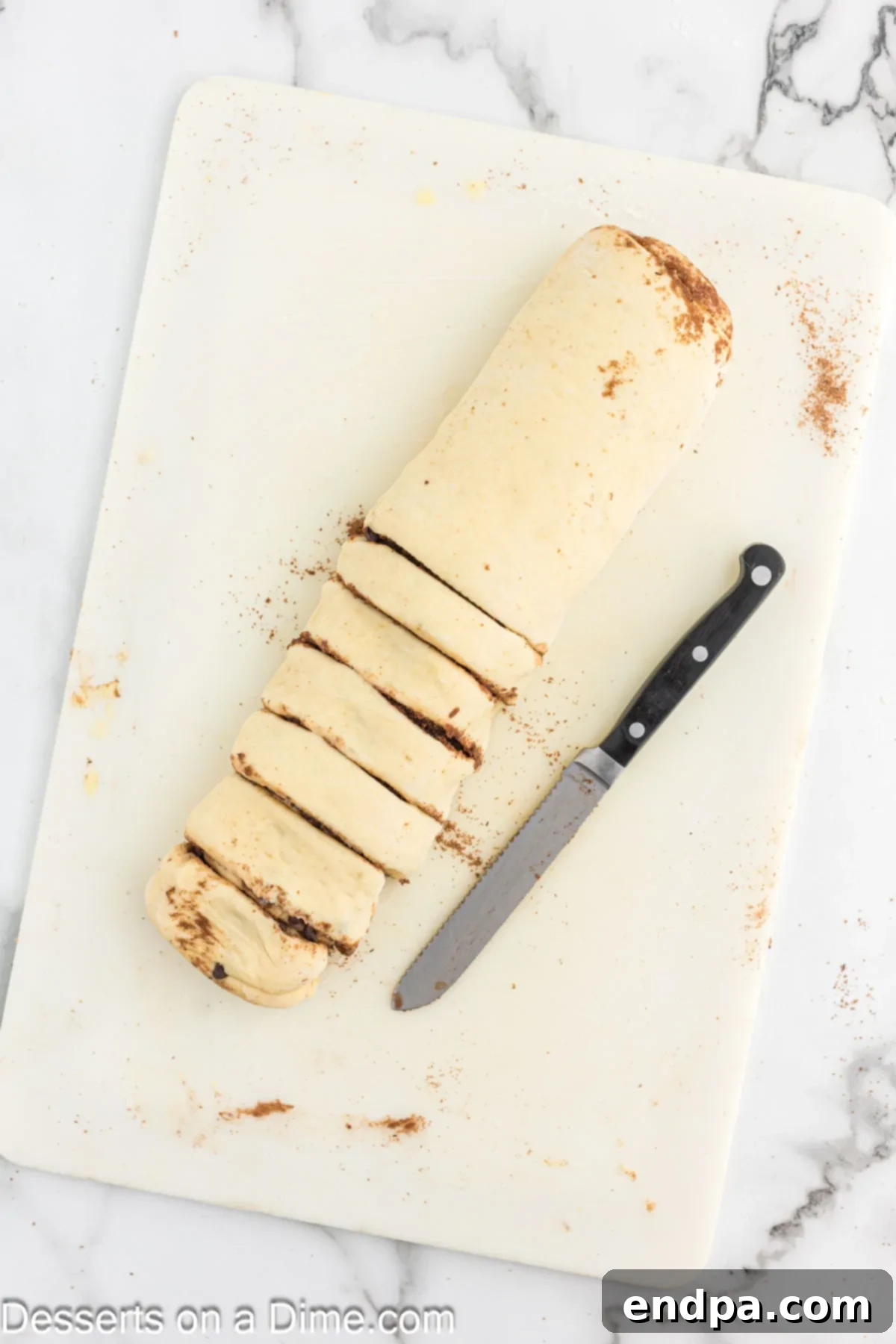 Rolled dough cut into even slices using a serrated knife.