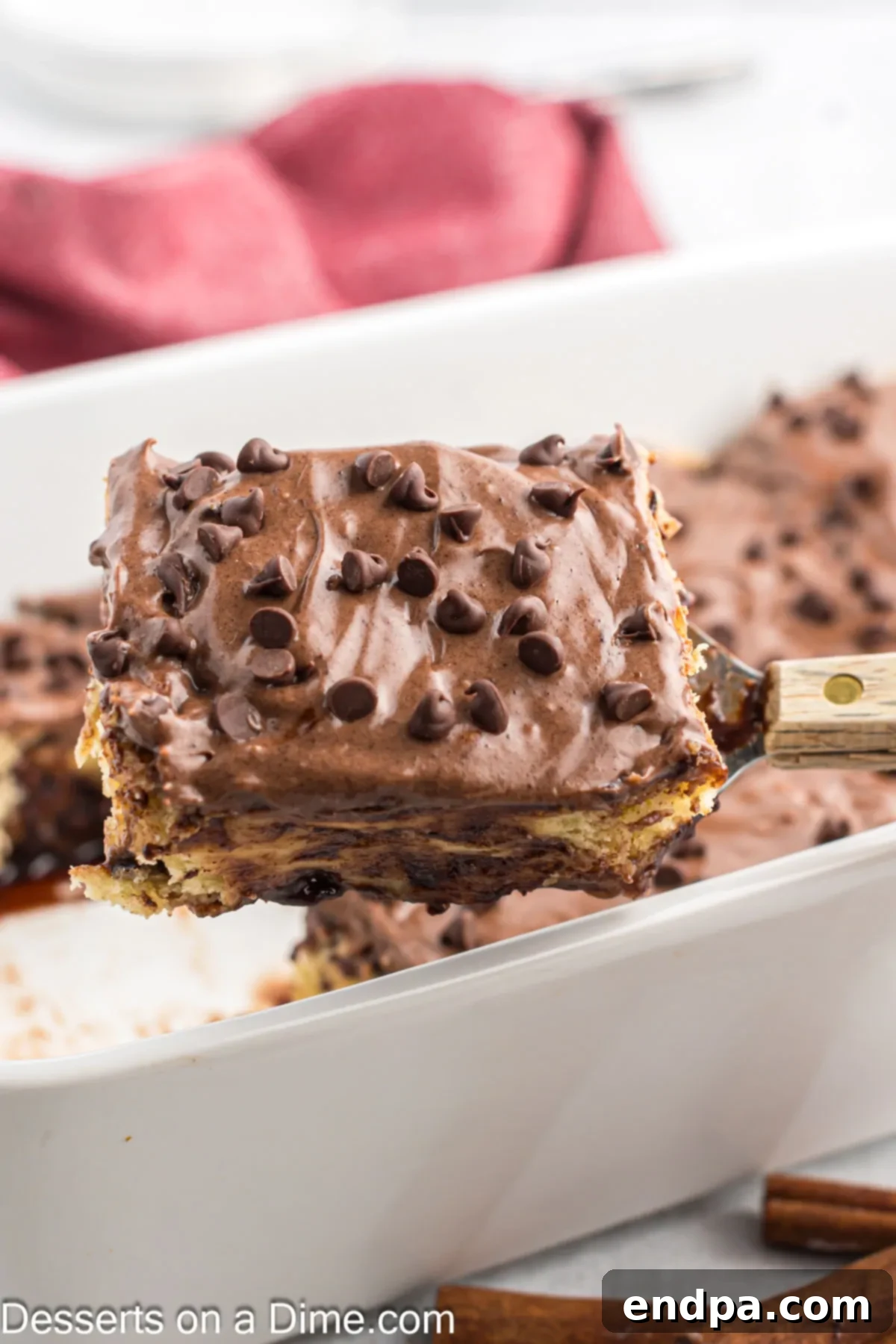 A freshly baked Chocolate Chip Cinnamon Roll being served from a baking dish, ready to be enjoyed.