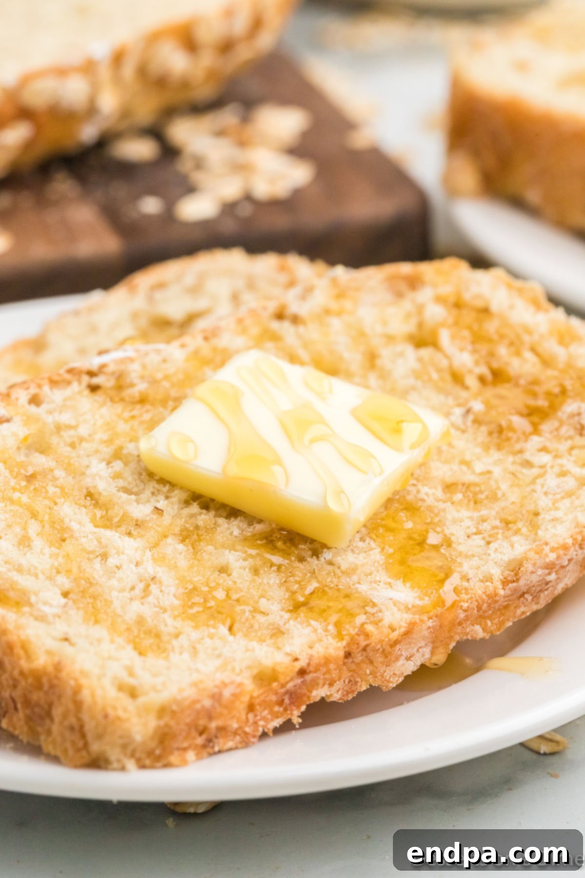 A freshly baked loaf of golden-brown homemade oatmeal bread, sliced and ready to serve.