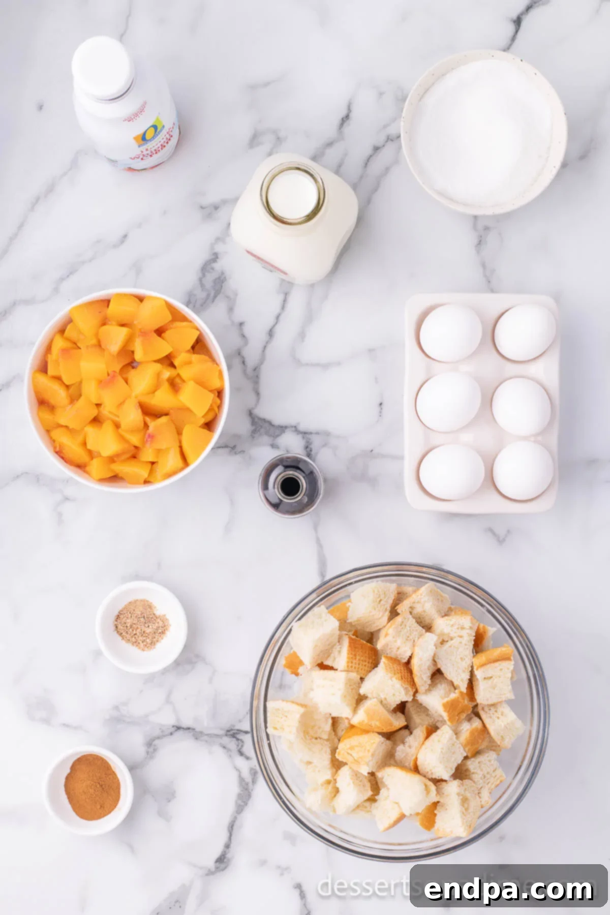 Summer Peach Bread Delight 3 Various ingredients for peach bread pudding laid out on a wooden surface, including bread cubes, eggs, milk, cream, sugar, vanilla, cinnamon, nutmeg, and fresh peaches.