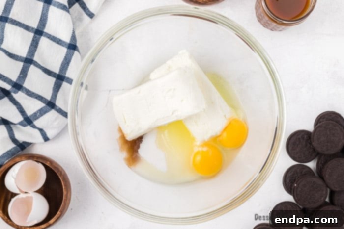 Ultimate Decadence Cheesecake Bars 5 A bowl containing cream cheese, sugar, eggs, and vanilla, combined and ready to be mixed for the cheesecake filling.