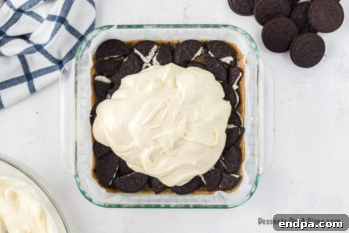 Ultimate Decadence Cheesecake Bars 7 Creamy cheesecake mixture being poured and spread evenly over the layer of Oreo cookies.