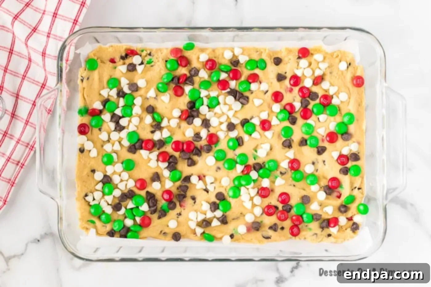 Joyful Christmas Cookie Bars 5 The cookie dough mixture being pressed evenly into the 9x13 inch baking dish.