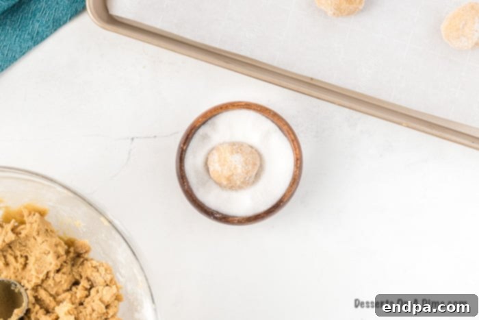Cookie dough balls rolled in granulated sugar, ready for baking.