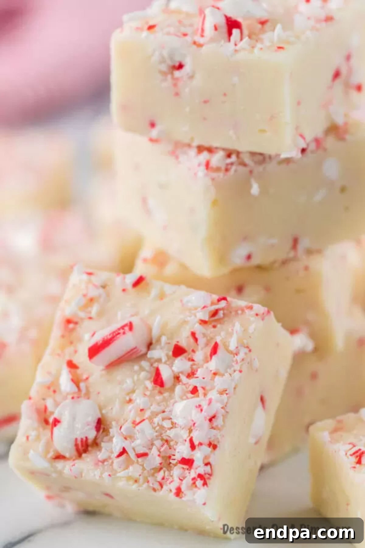 Peppermint Fudge cut into squares and stacked together on a festive plate.