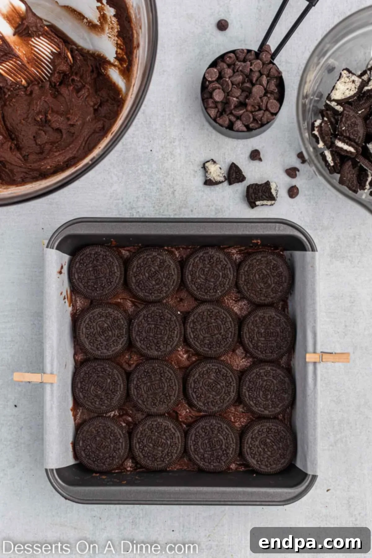 Whole Oreo cookies placed neatly on top of the first layer of brownie batter in the pan.