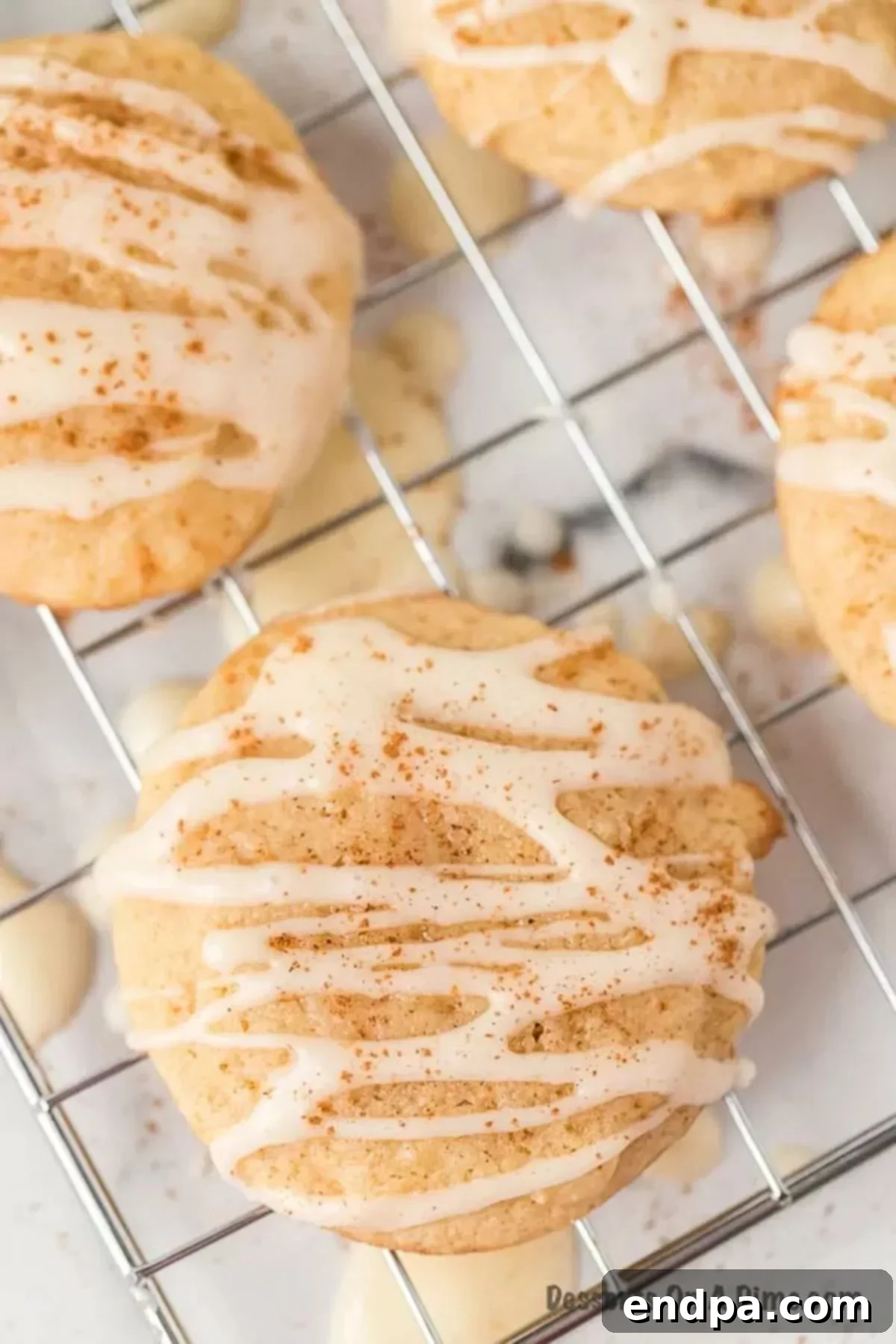 A single eggnog cookie resting on a wire cooling rack, perfectly frosted and spiced.