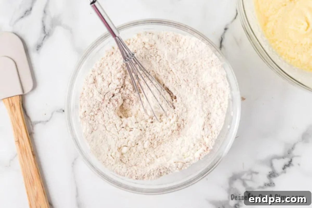 A separate bowl containing dry ingredients like flour, baking powder, nutmeg, and cinnamon.