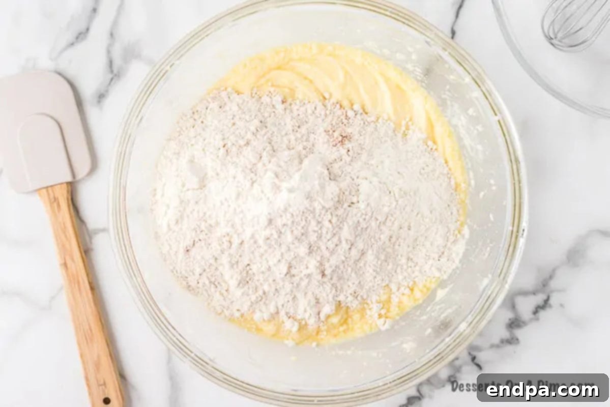Dry ingredients being gently mixed into the wet ingredients by hand.