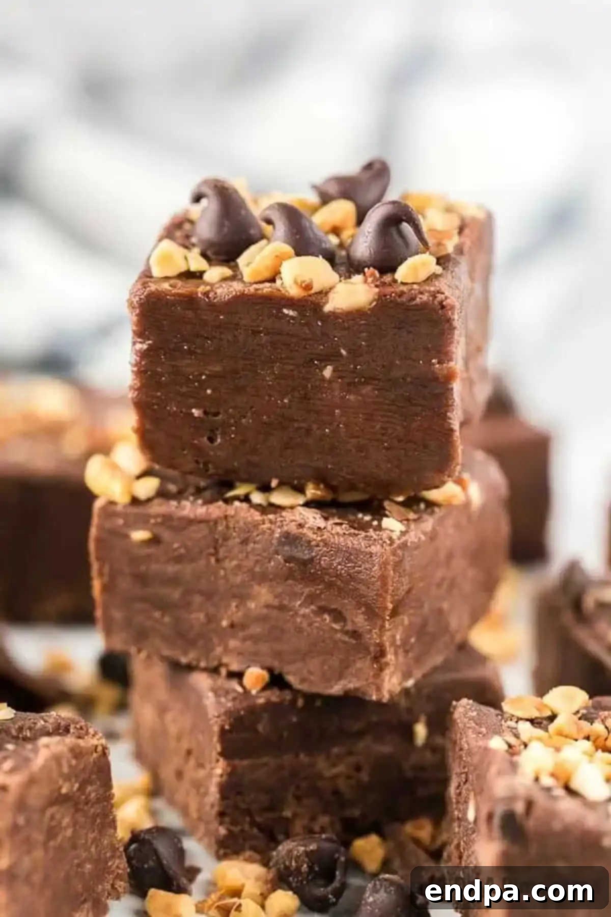 Stacked squares of chocolate peanut butter fudge, perfectly cut and ready to be served, highlighting their inviting layers.