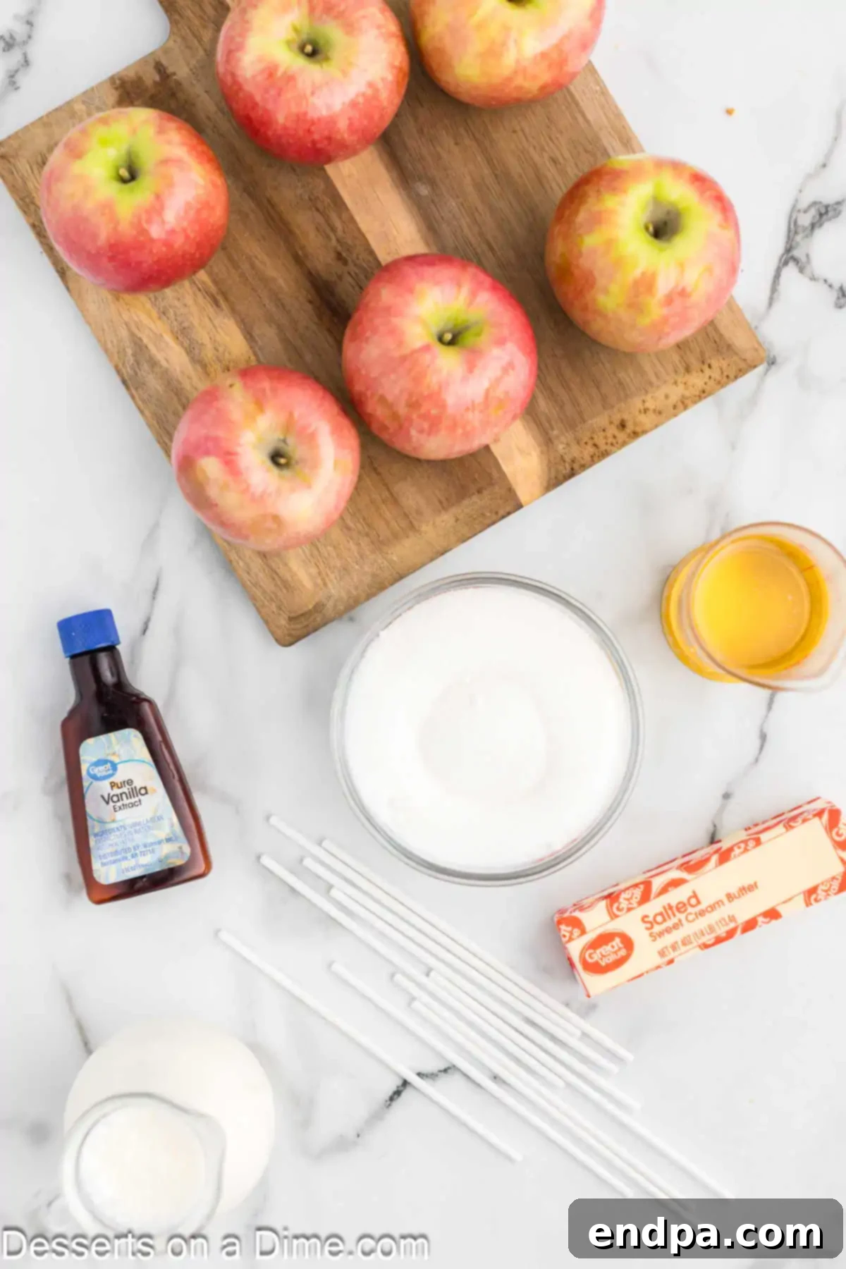 A beautiful flat lay of ingredients for making caramel apples, including fresh green apples, brown sugar, butter, heavy cream, and vanilla extract.