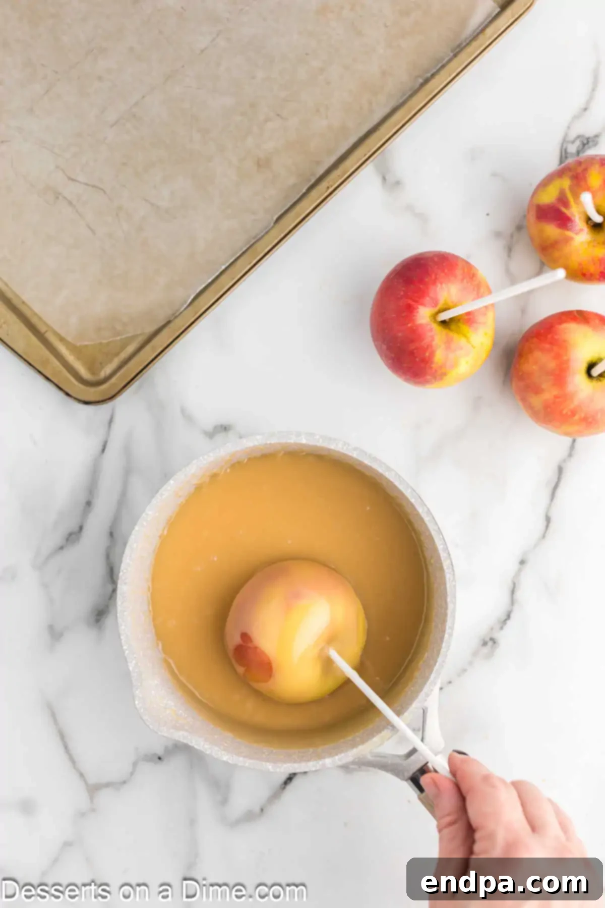 A green apple being dipped into a luscious, golden caramel mixture in a saucepan, ensuring even coating.