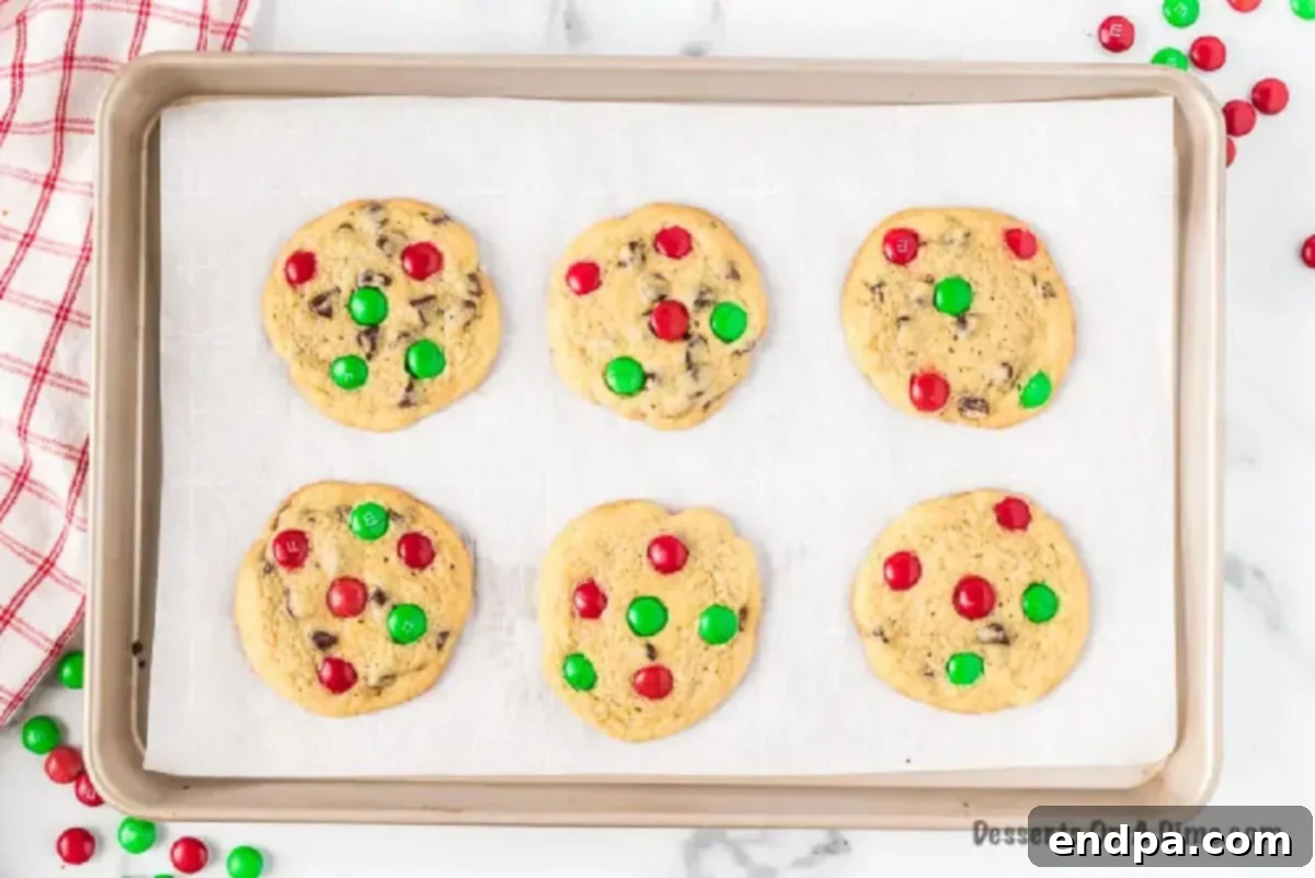 Deliciously Simple Santa Cookies 5 Baked Santa Cookies cooling on a baking sheet, golden brown with melted M&Ms