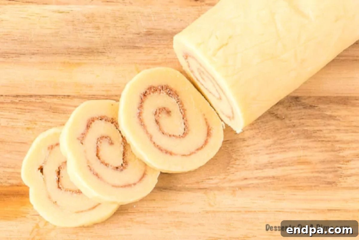 Rolled dough log being cut into individual cookie slices.