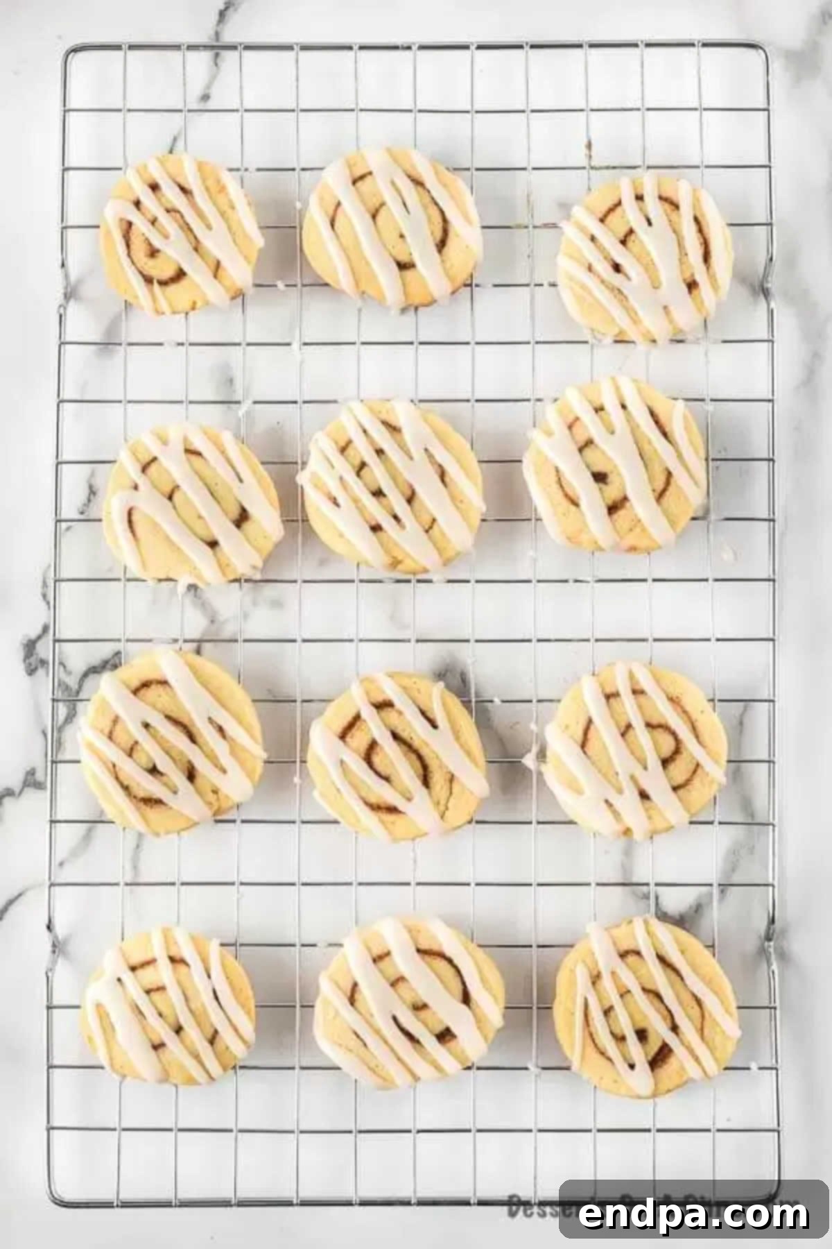 Freshly baked cinnamon roll cookies cooling on a wire rack, ready for icing.