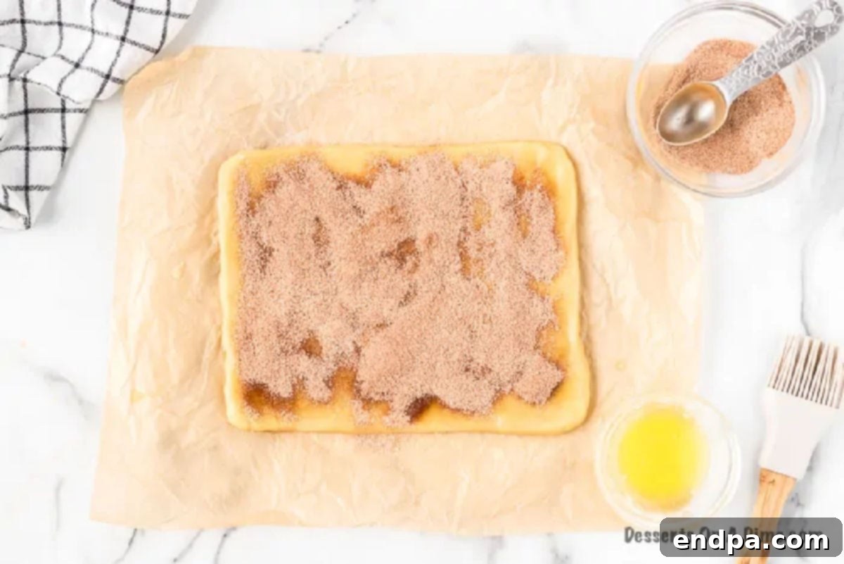 Cinnamon sugar mixture evenly sprinkled on top of the buttered dough.