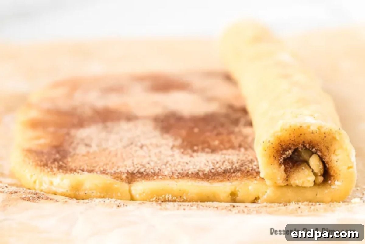 Dough being carefully rolled into a log shape.