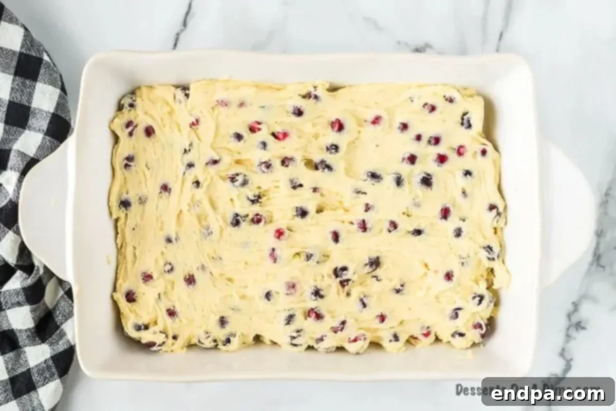 Cranberry cake batter spread evenly into the baking pan.