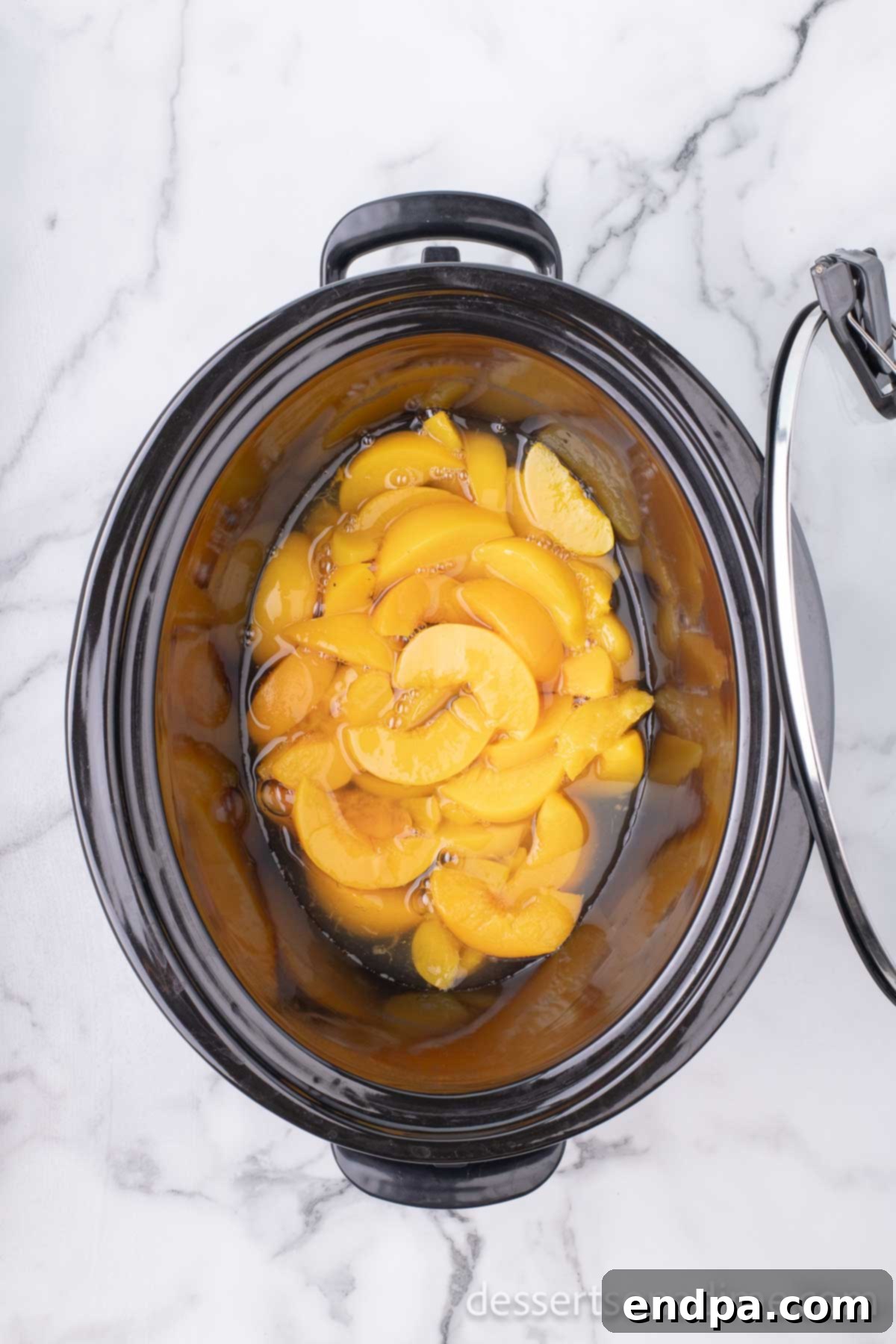 Three cans of peaches, with their heavy syrup, poured into the bottom of a 6-quart slow cooker, creating the juicy base for the dump cake.