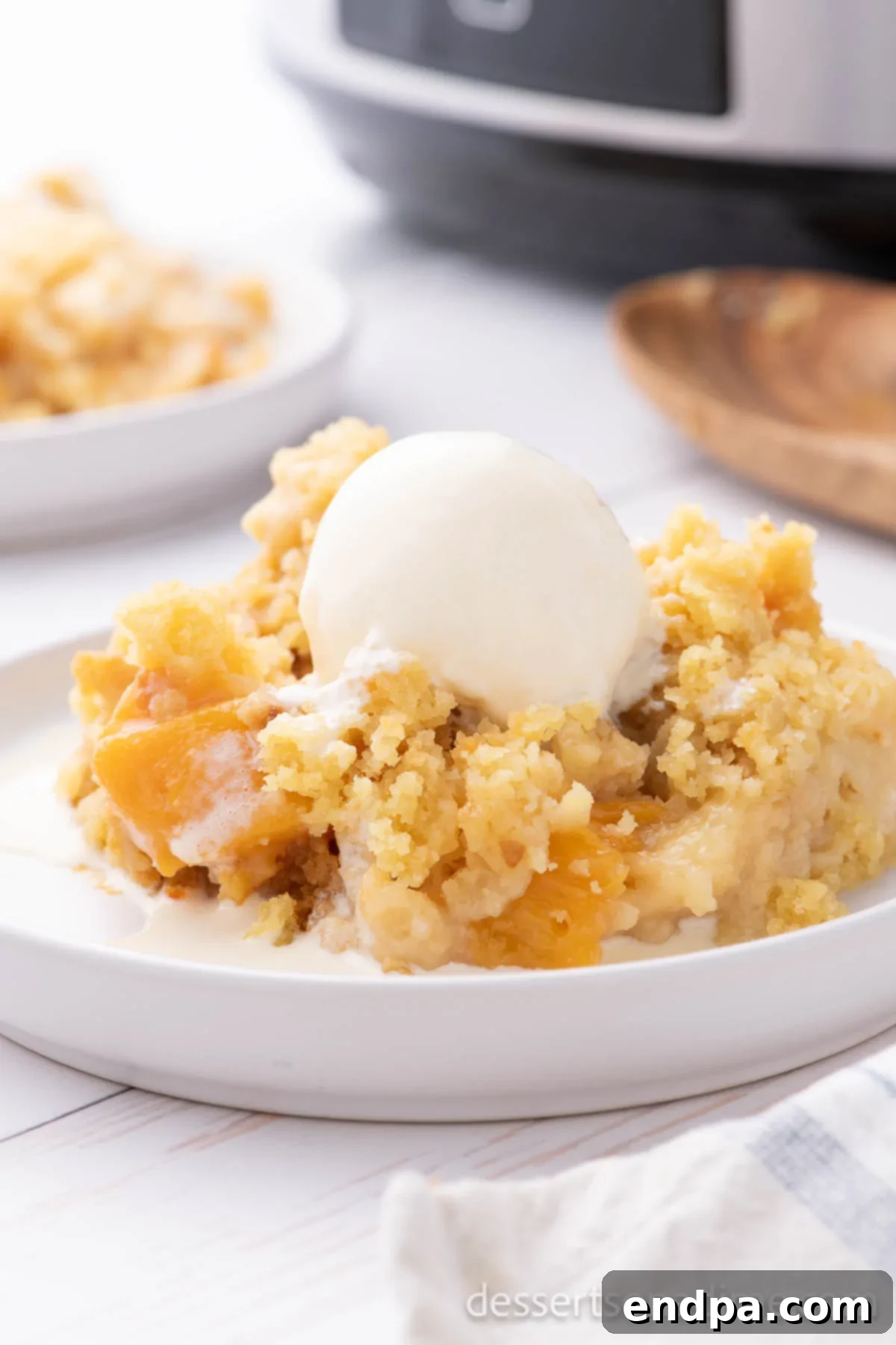 A full view of the Crock Pot Peach Dump Cake, freshly cooked, with a golden-brown cake topping and visible juicy peaches beneath, ready to be served.