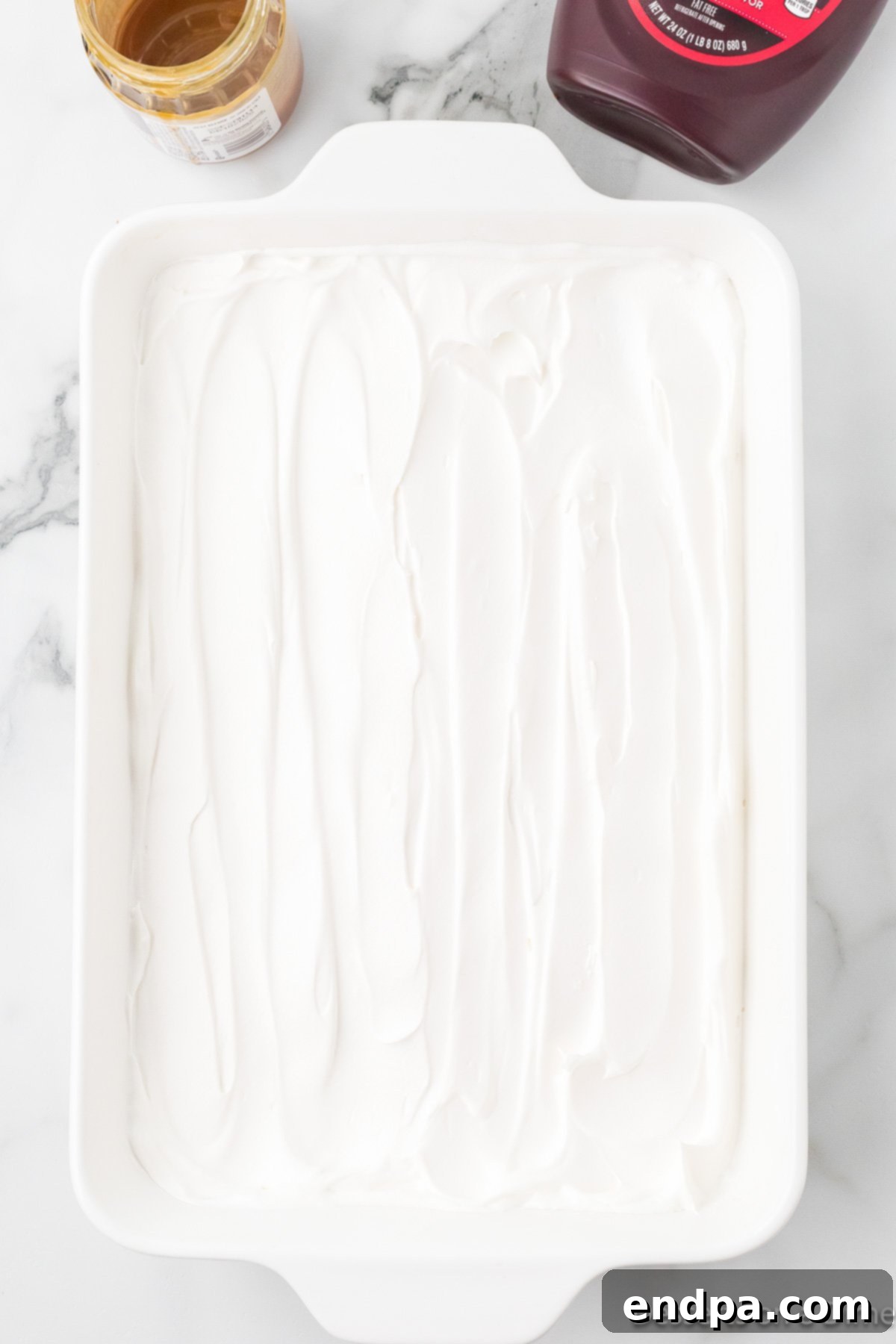 Gooey Chocolate Caramel Poke Cake 7 Whipped cream spread over cake.