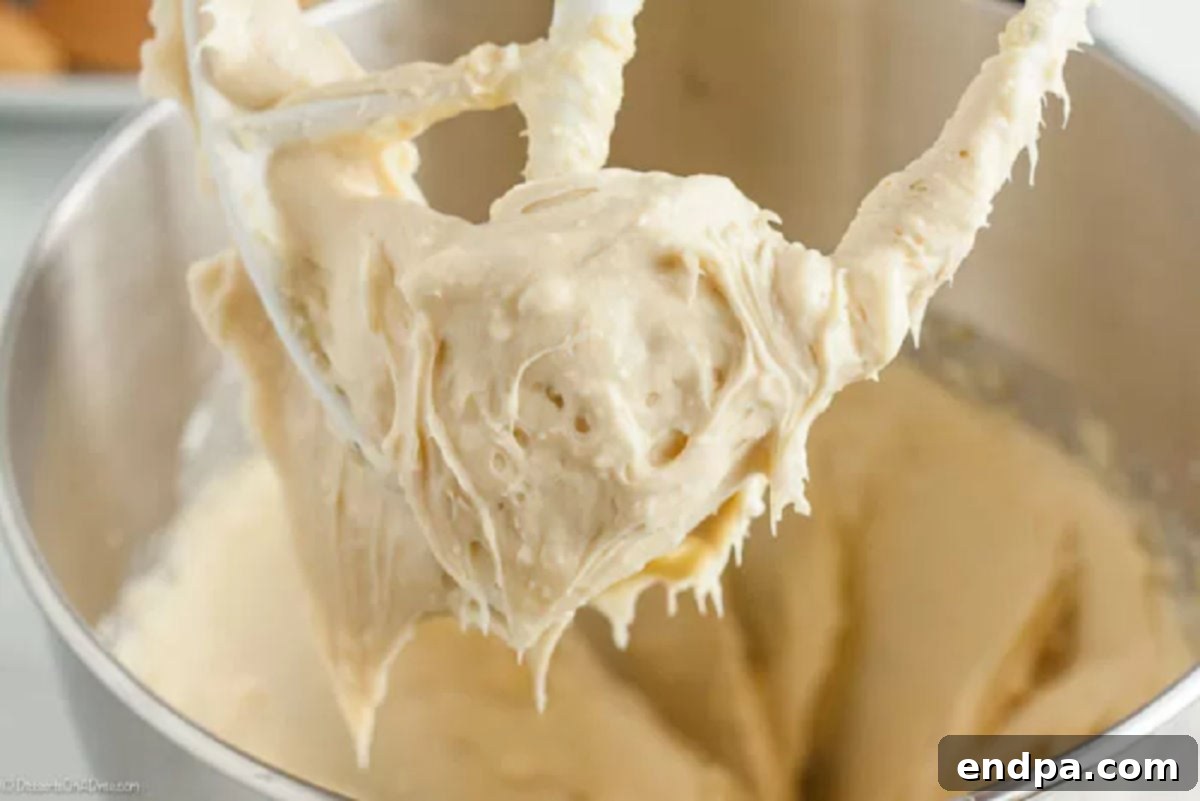 Softened butter, cream cheese, and sugars being creamed together in a stand mixer bowl until smooth.