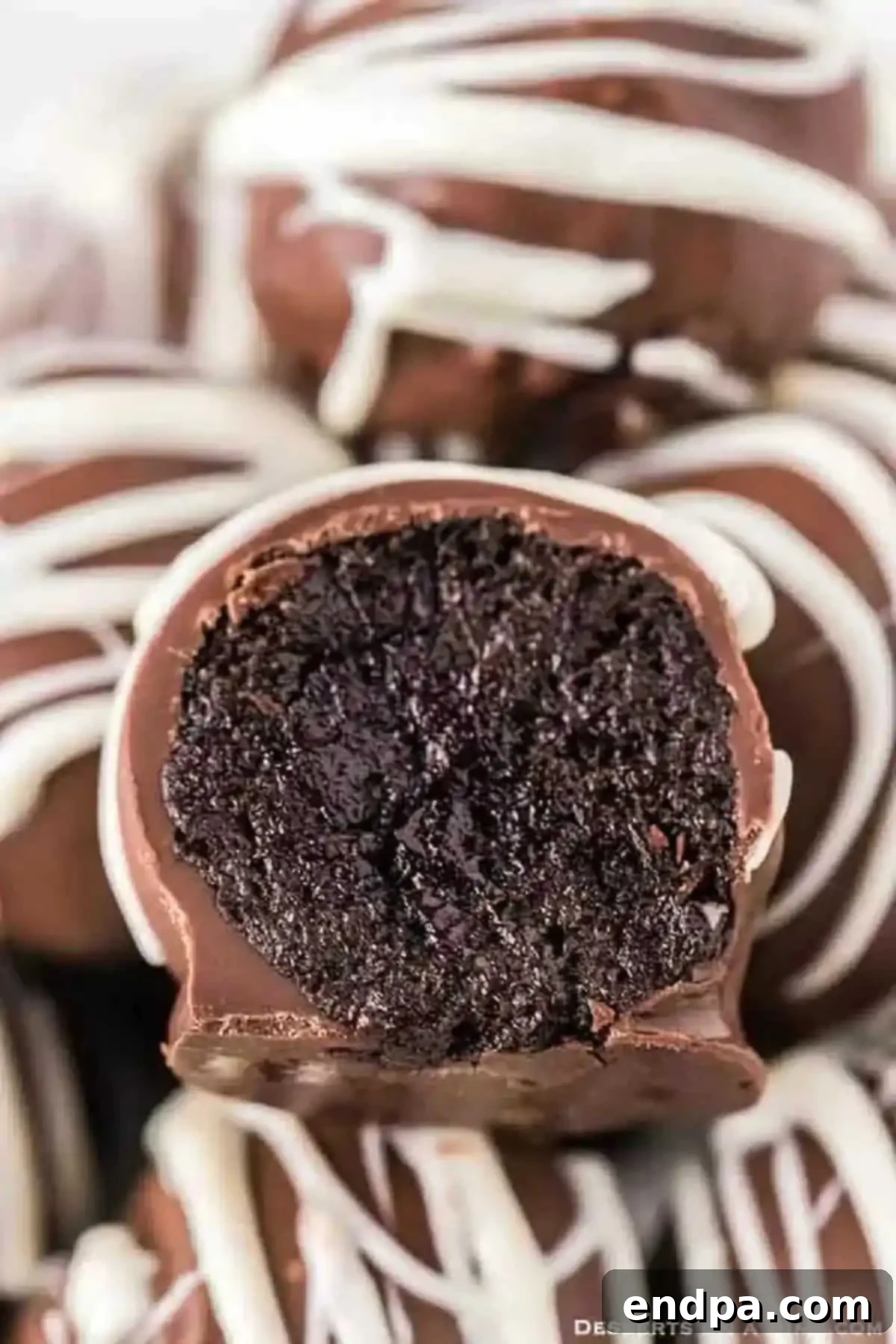 Discover the best chocolate covered no bake Oreo Balls recipe. These easy homemade Oreo truffles with cream cheese are perfect for Thanksgiving, Christmas, and any celebration. #oreoballs #recipe #nobake #chocolatetruffles No Bake Oreo Balls stacked, garnished with a drizzle of white chocolate