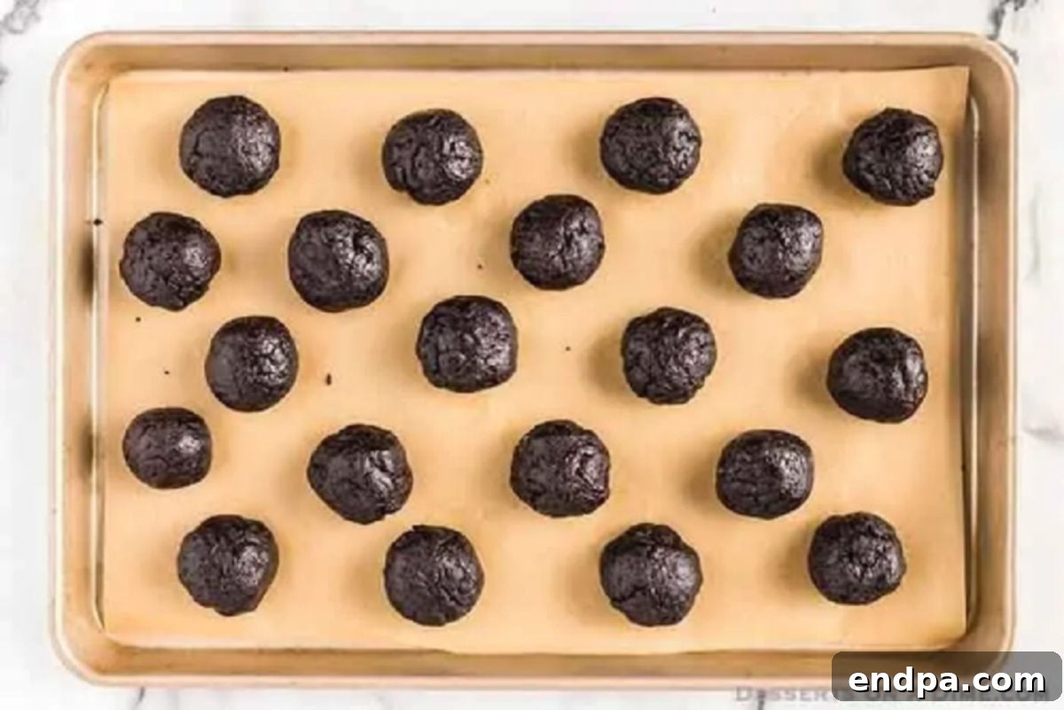 Decadent No-Bake Oreo Truffles 4 Oreo Balls on a baking sheet, ready to be frozen